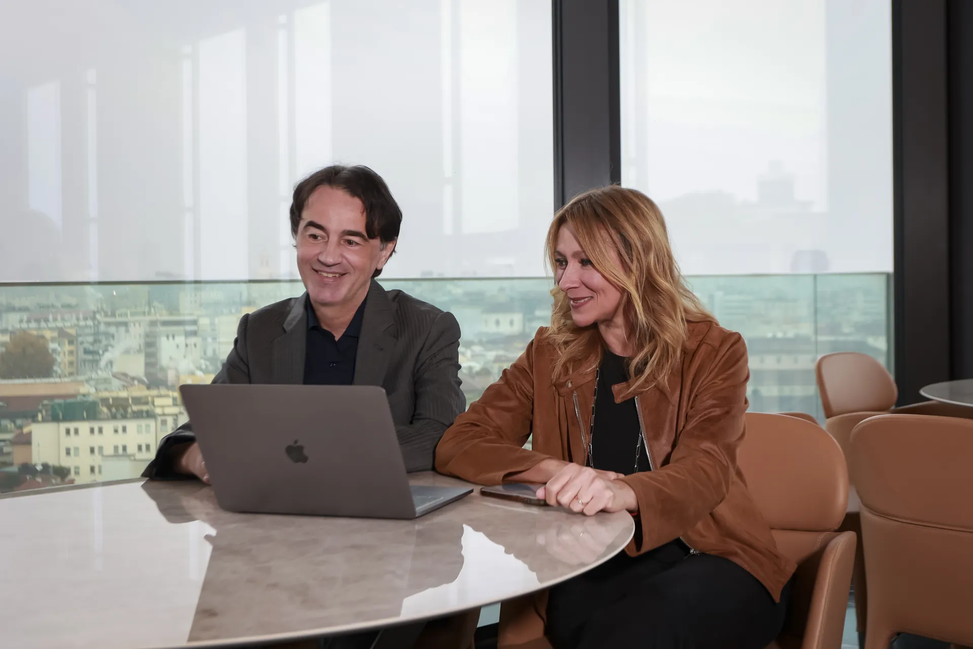 I fondatori di Komax al lavoro davanti al laptop, con vista su Milano
