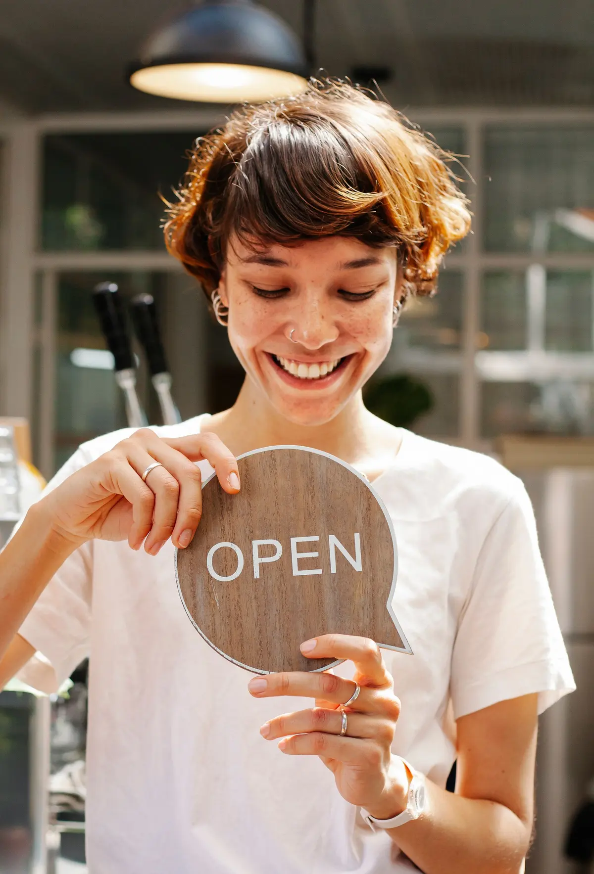 Titolare sorridente con il cartello Open della sua attività