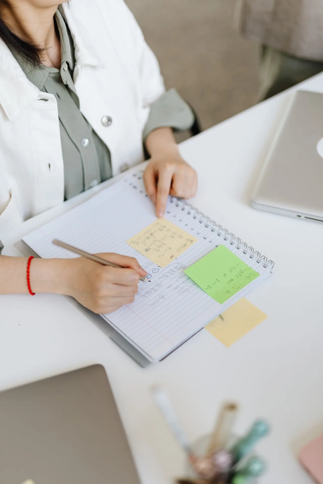 Mani che scrivono appunti su un quaderno con i post-it